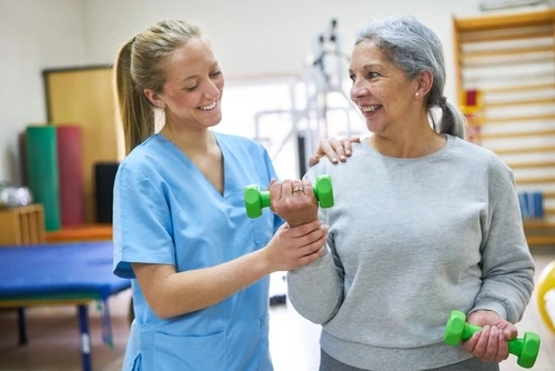 Fisioterapista che guida un paziente in un esercizio di rinforzo muscolare post-operatorio.